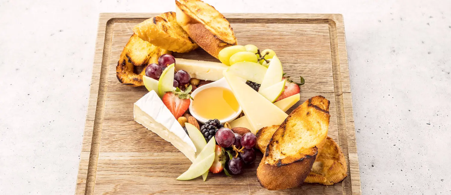 Cheese platter with assorted fruits, nuts, and grilled bread