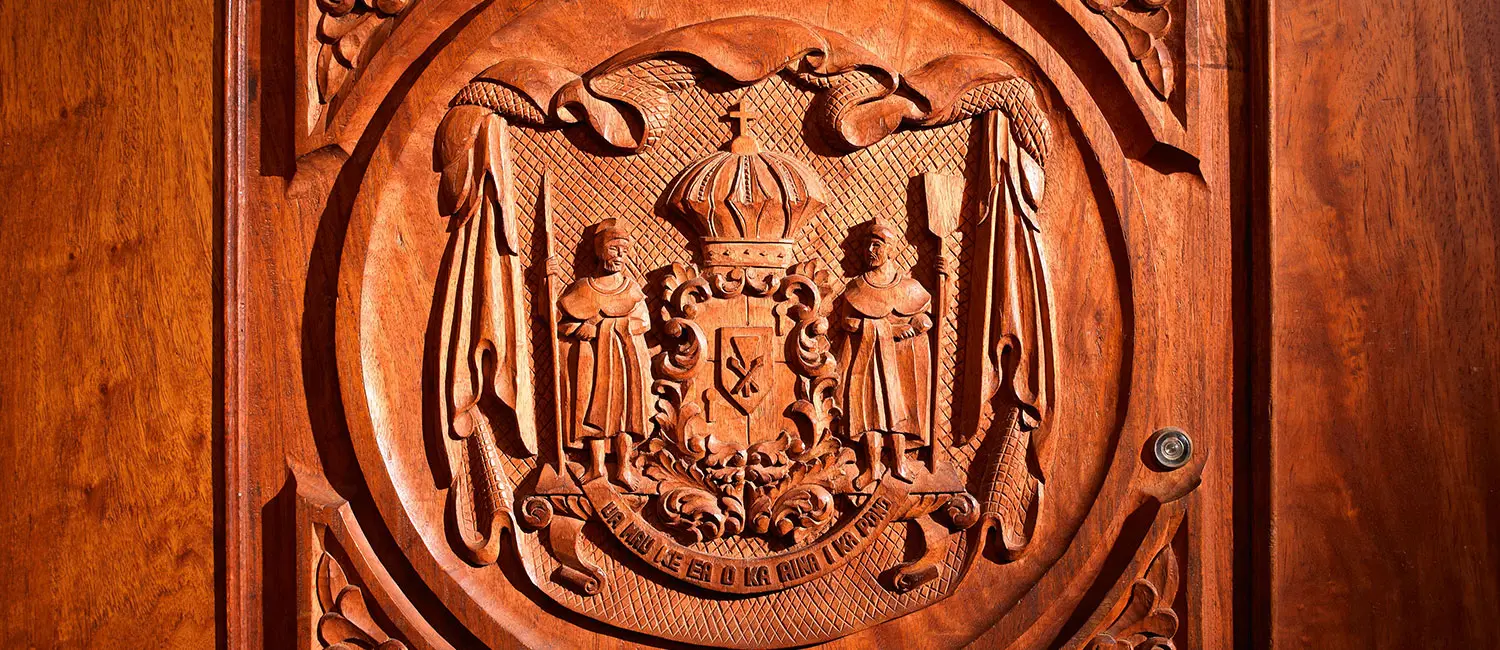 Wooden door featuring the carved Hawaiian royal coat of arms in the Historic Wing.