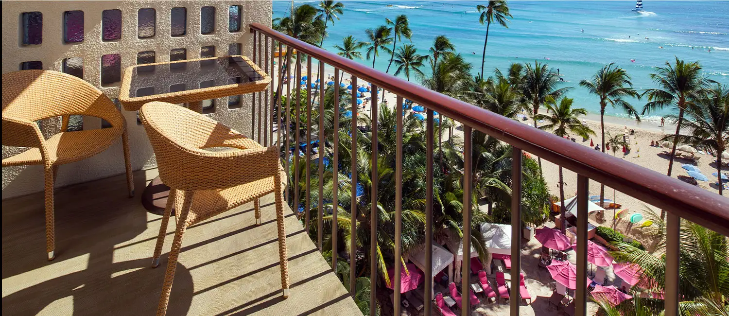 View of Waikiki Beach from the balcony with rows of pink umbrellas.