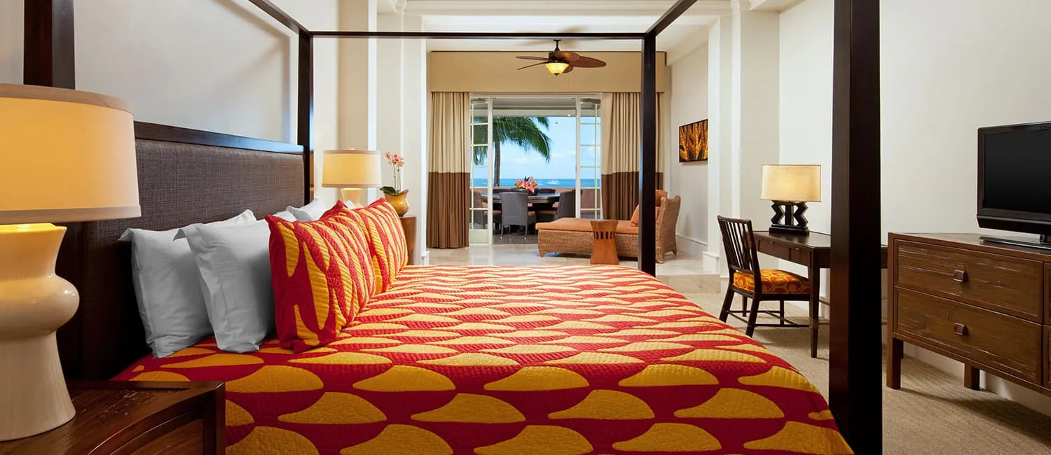 Bedroom of the Kamehameha Suite featuring vibrant red and orange bed cover.