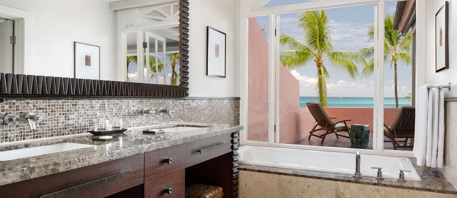 Bathroom of the Kamehameha Suite with a view of the blue ocean through large windows.