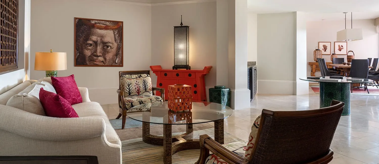 The Queen Ka‘ahumanu Suite living and dining area featuring artwork and red furnishings.