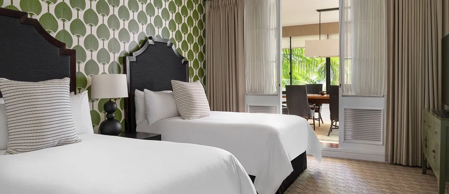 Bedroom with twin beds and green-patterned wallpaper.