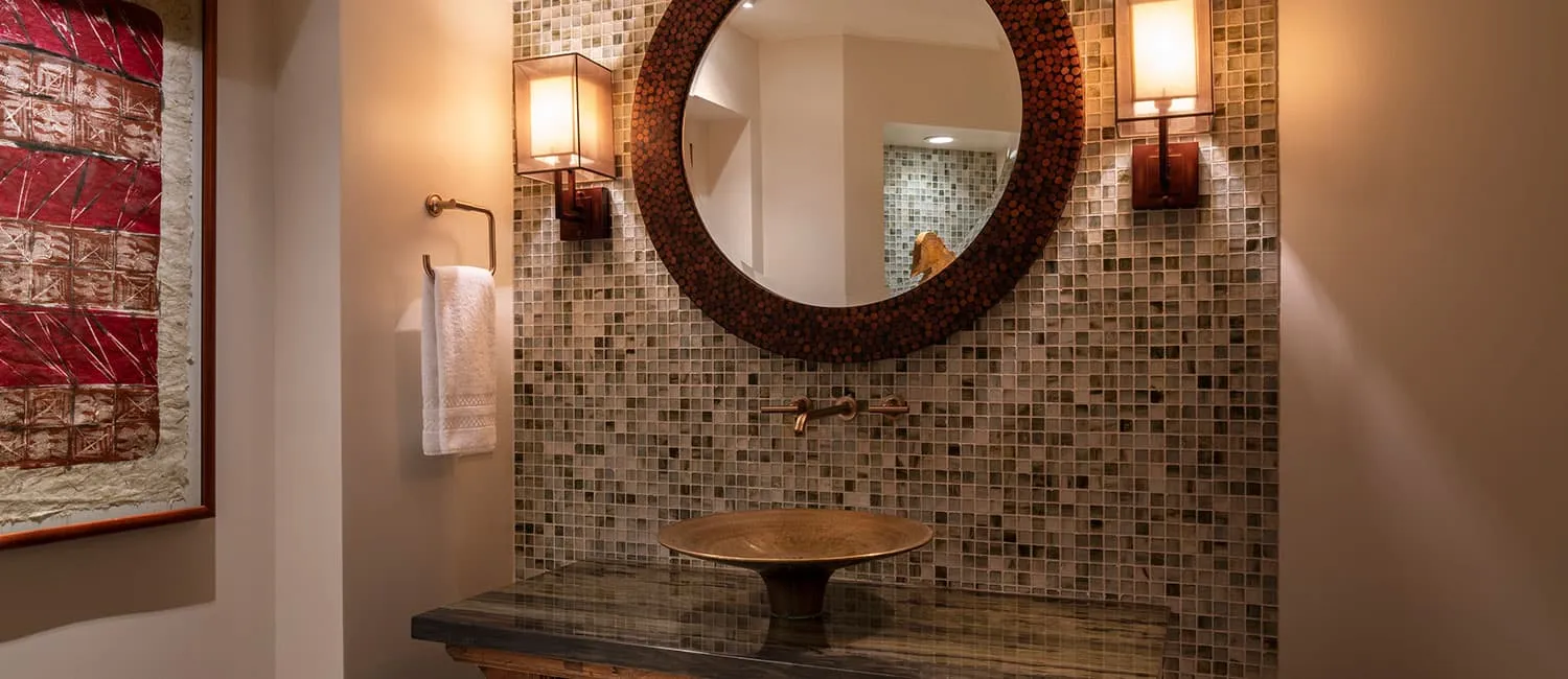 Vanity area featuring a round mirror and mosaic tile wall.
